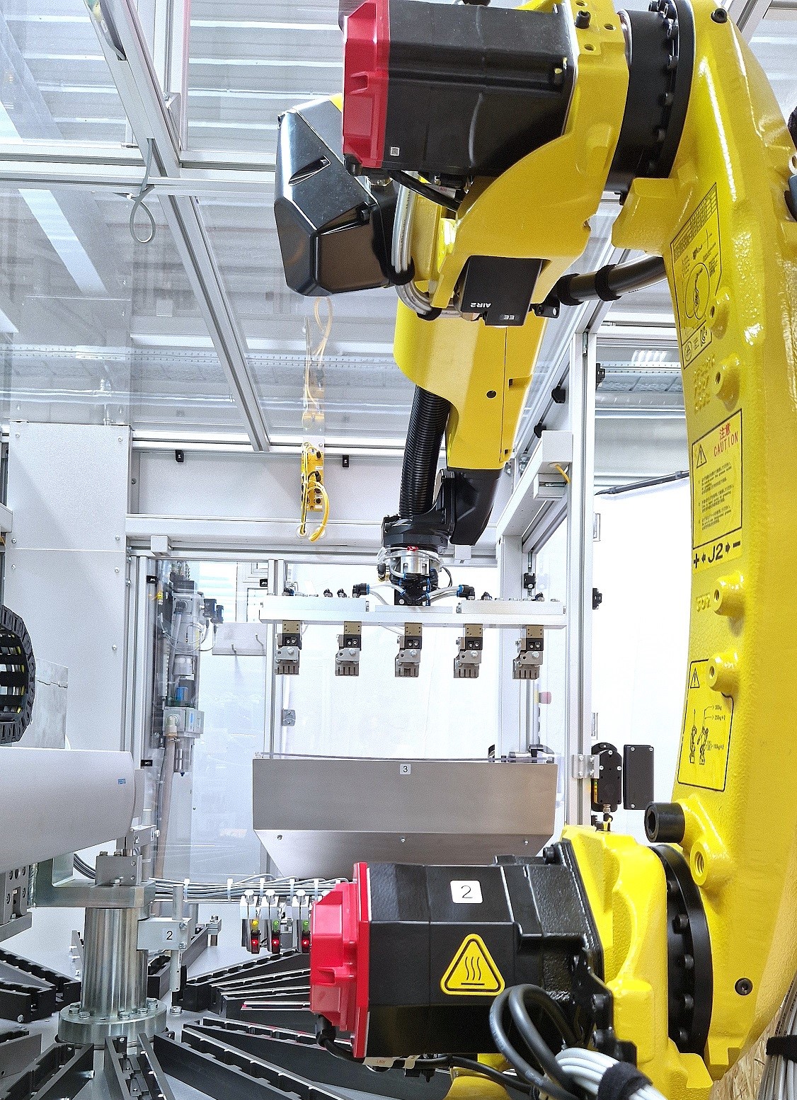 Bras robotisé jaune avec pince à 5 positions dans une machine d'assemblage