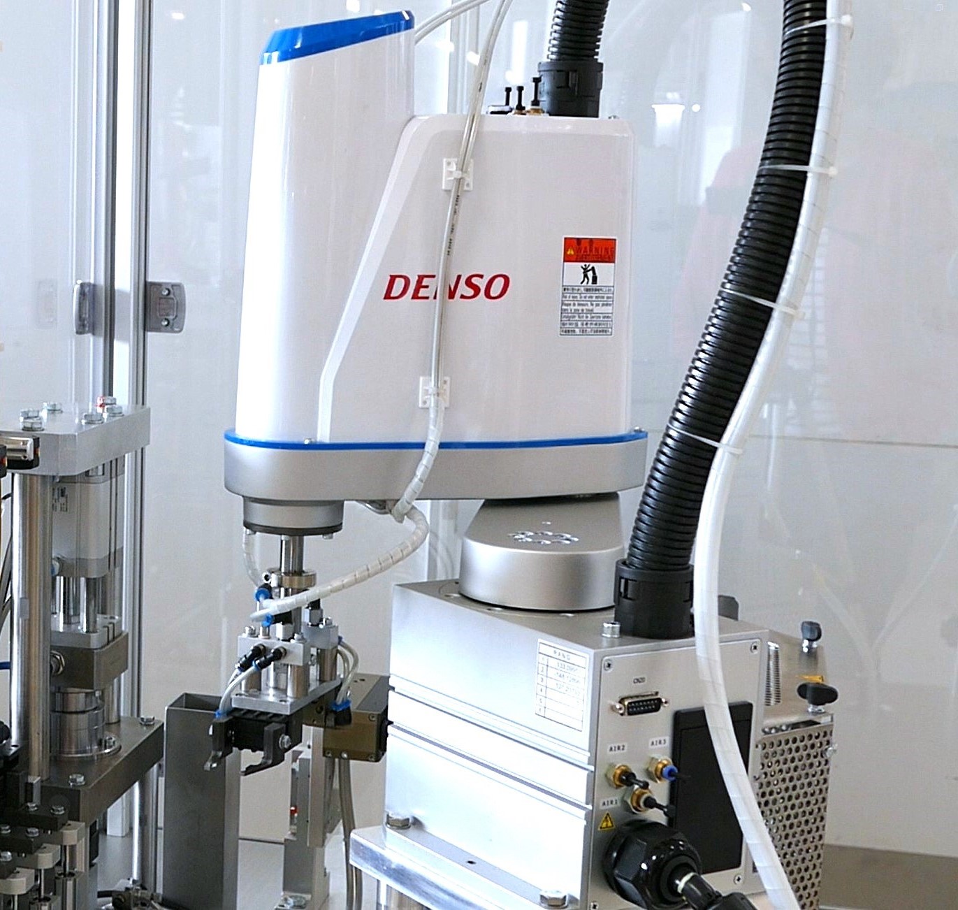 robot SCARA blanc avec double préhenseur dans une machine d'assemblage
